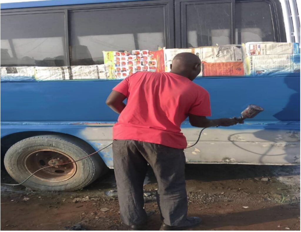 Sydney painting a bus in Zambia
